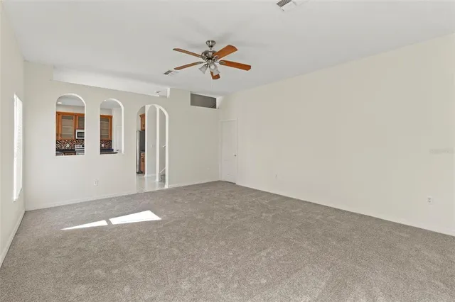 an empty room with windows and ceiling fan view