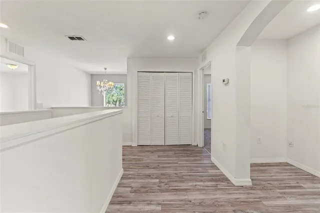 a view of a hallway with wooden floor and a bathroom