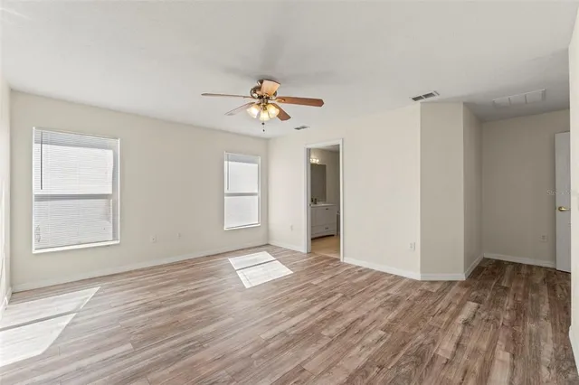 a view of an empty room with window and wooden floor