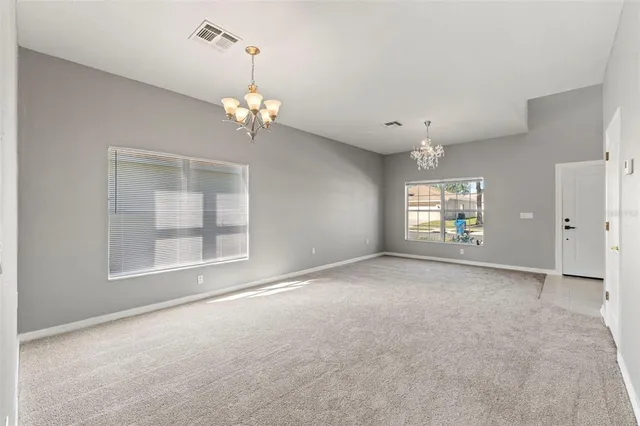 an empty room with a windows and chandelier fan