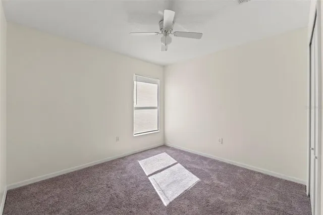an empty room with a ceiling fan and window