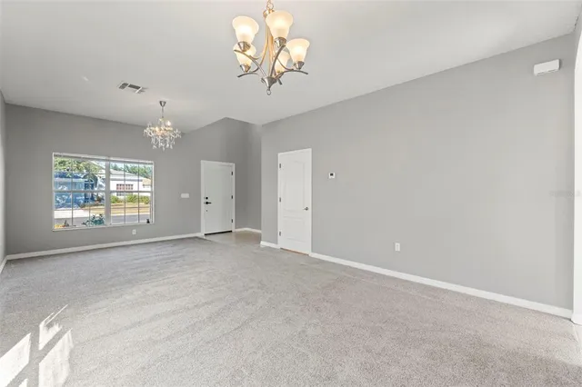 an empty room with a chandelier fan and windows