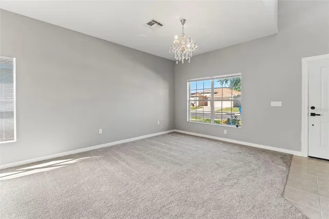 en empty room with windows and chandelier fan