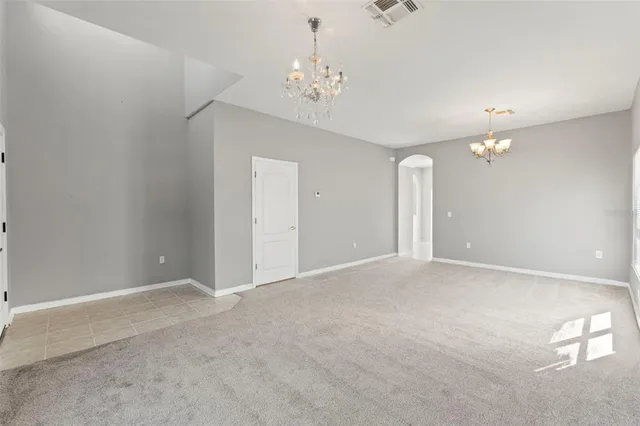 a view of an empty room with a chandelier fan