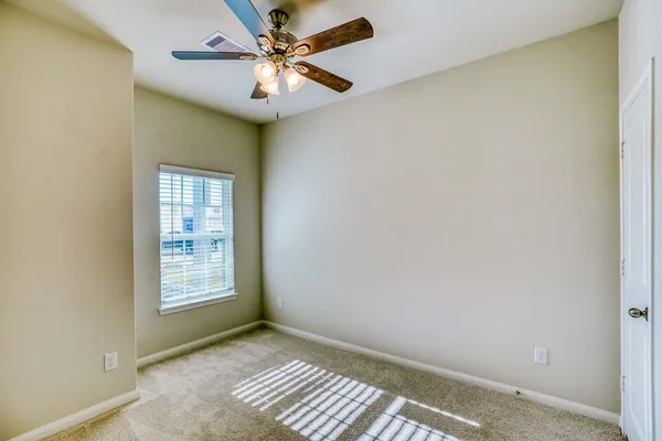 an empty room with windows and fan