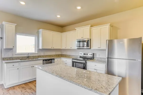 a kitchen with stainless steel appliances granite countertop a refrigerator sink stove and white cabinets