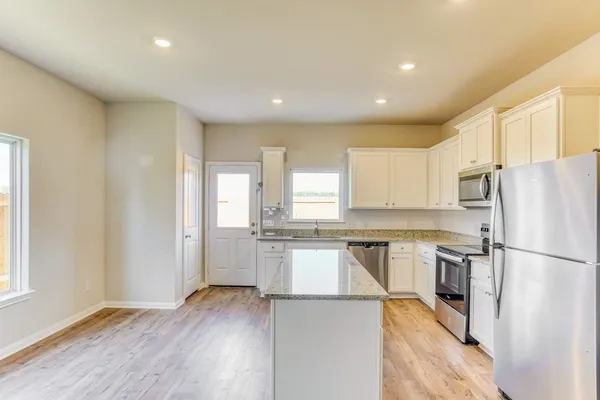 a kitchen with a refrigerator a sink and wooden floor
