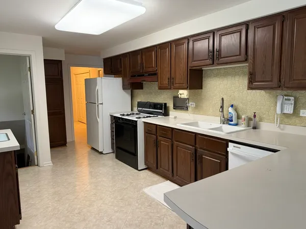a kitchen with stainless steel appliances a sink a stove a refrigerator cabinets and a window