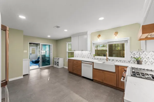 a large white kitchen with stainless steel appliances granite countertop a large counter top and sink