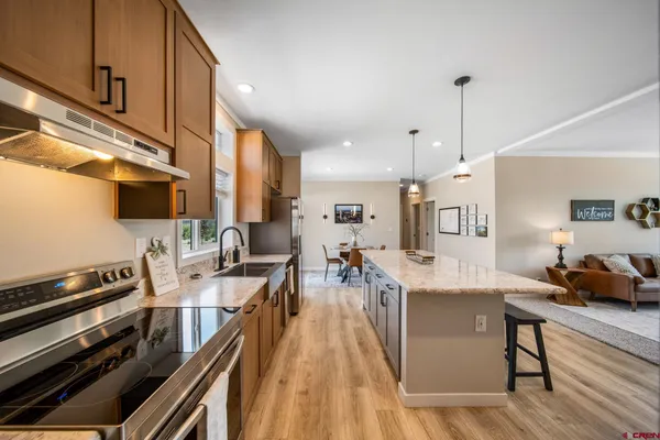 a living room with stainless steel appliances kitchen island granite countertop furniture and a wooden floor