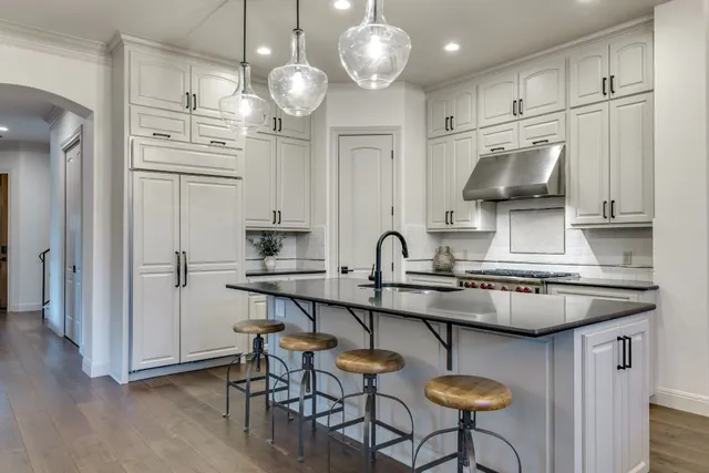 a kitchen with stove a sink dishwasher a dining table and chairs a fireplace with wooden floor