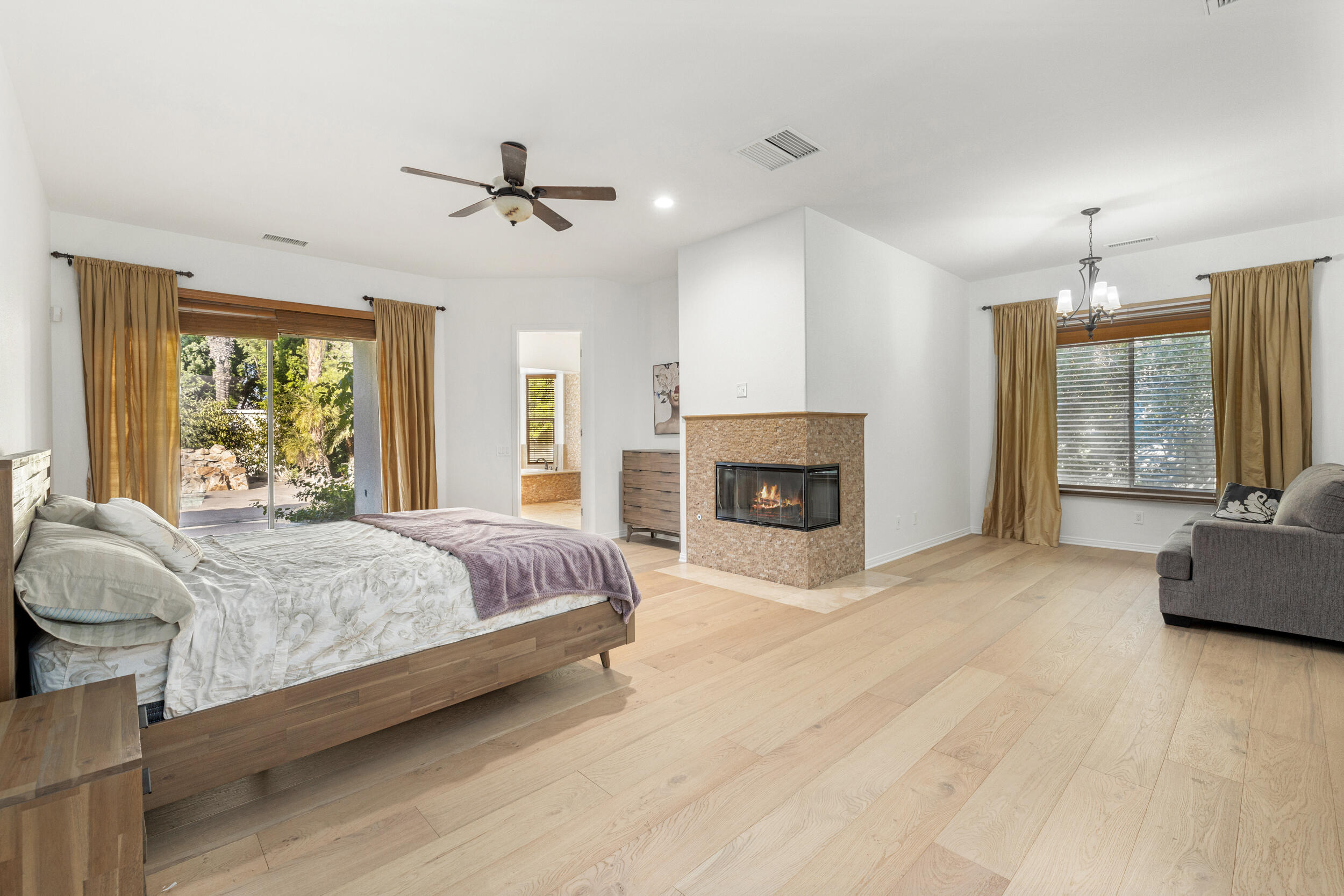 8 Trafalgar Rancho Mirage, CA 92270 - Photo 14 of 41 a spacious bedroom with a large bed a chandelier and a fireplace