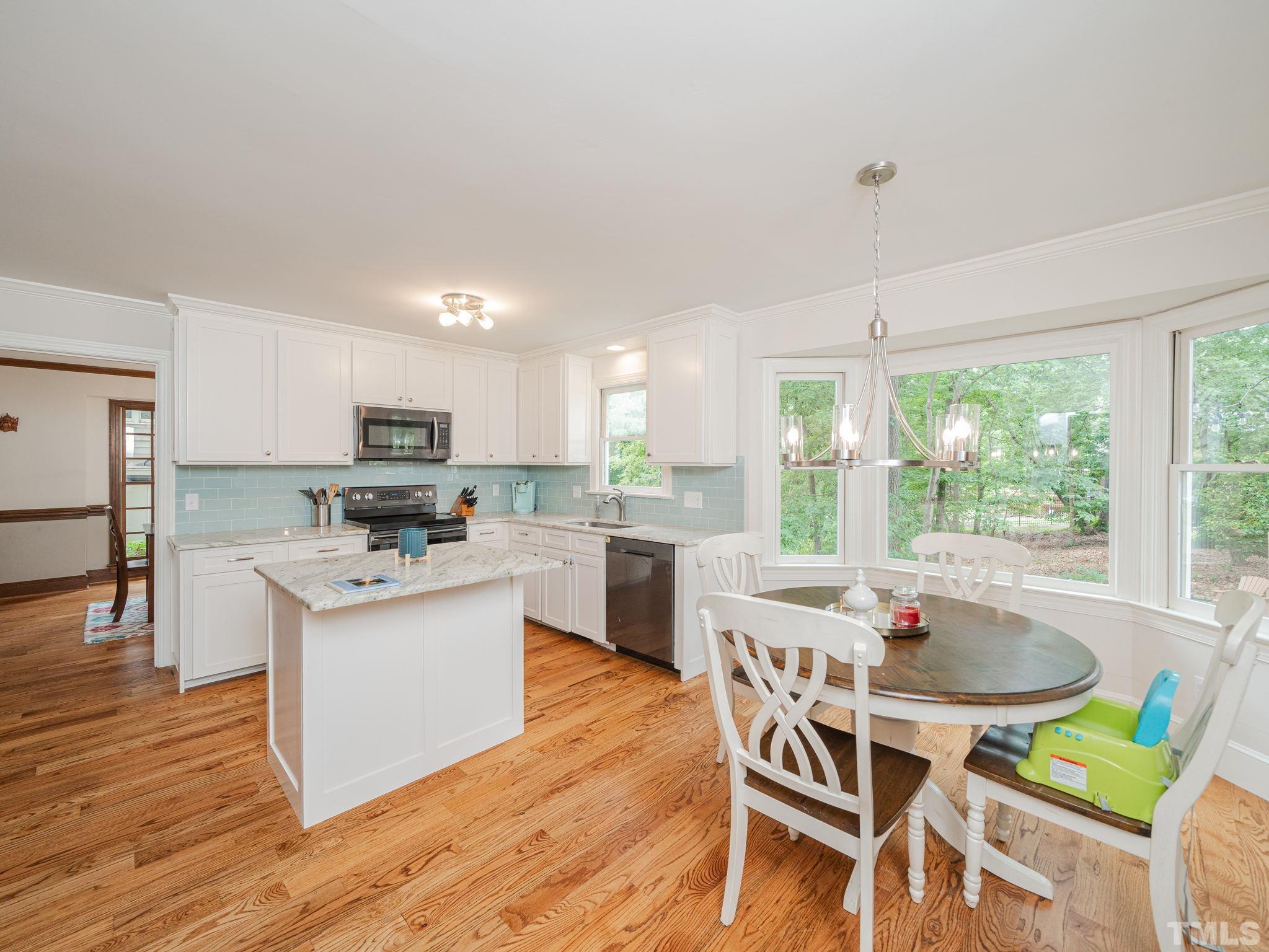 5029 Trail Ridge Drive Raleigh, NC 27613 - Photo 5 of 37 a kitchen with stainless steel appliances granite countertop a stove top oven a sink dishwasher a dining table and chairs with wooden floor