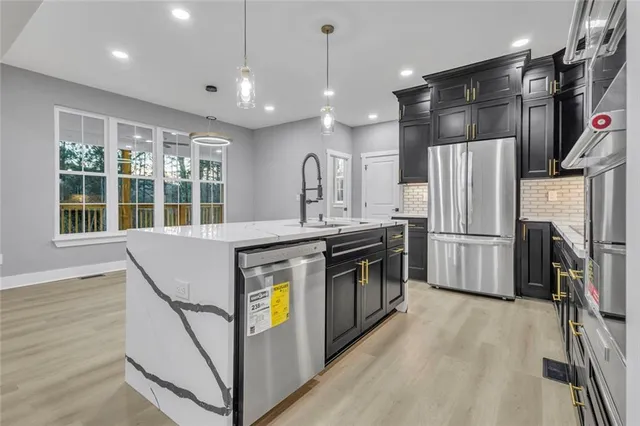 a kitchen with stainless steel appliances granite countertop a refrigerator a sink and a stove