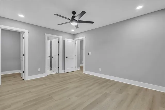 an empty room with wooden floor fan and windows