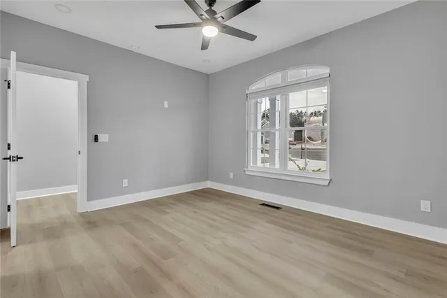 a view of an empty room with a window and wooden floor