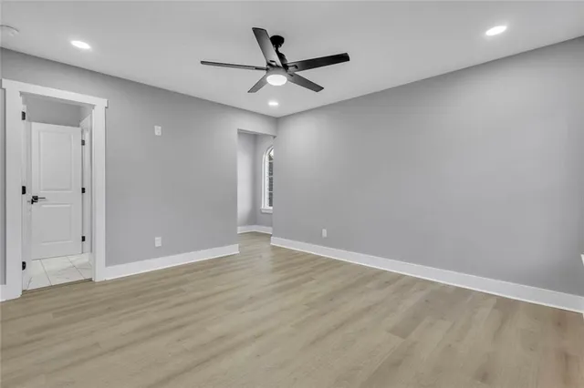 an empty room with wooden floor and a ceiling fan
