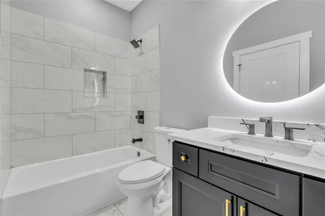 a bathroom with a granite countertop sink a toilet and bathtub