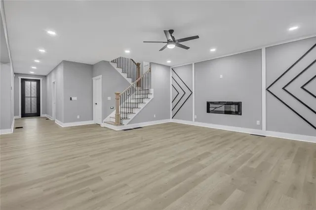 an empty room with wooden floor and a ceiling fan