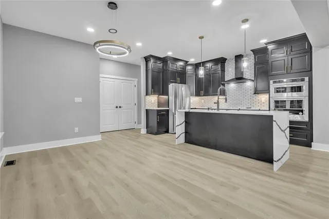 a large kitchen with stainless steel appliances kitchen island granite countertop a refrigerator and cabinets