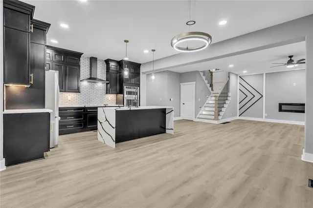 a living room with stainless steel appliances kitchen island a sink and a refrigerator