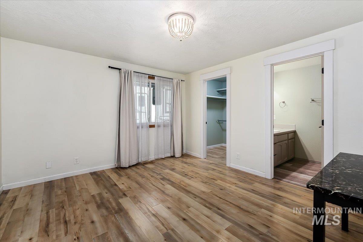 9215 West Preece Street Boise, ID 83704 - Photo 7 of 22 Room featuring wood-finish flooring, a decorative chandelier, and a window with sheer and blackout curtains