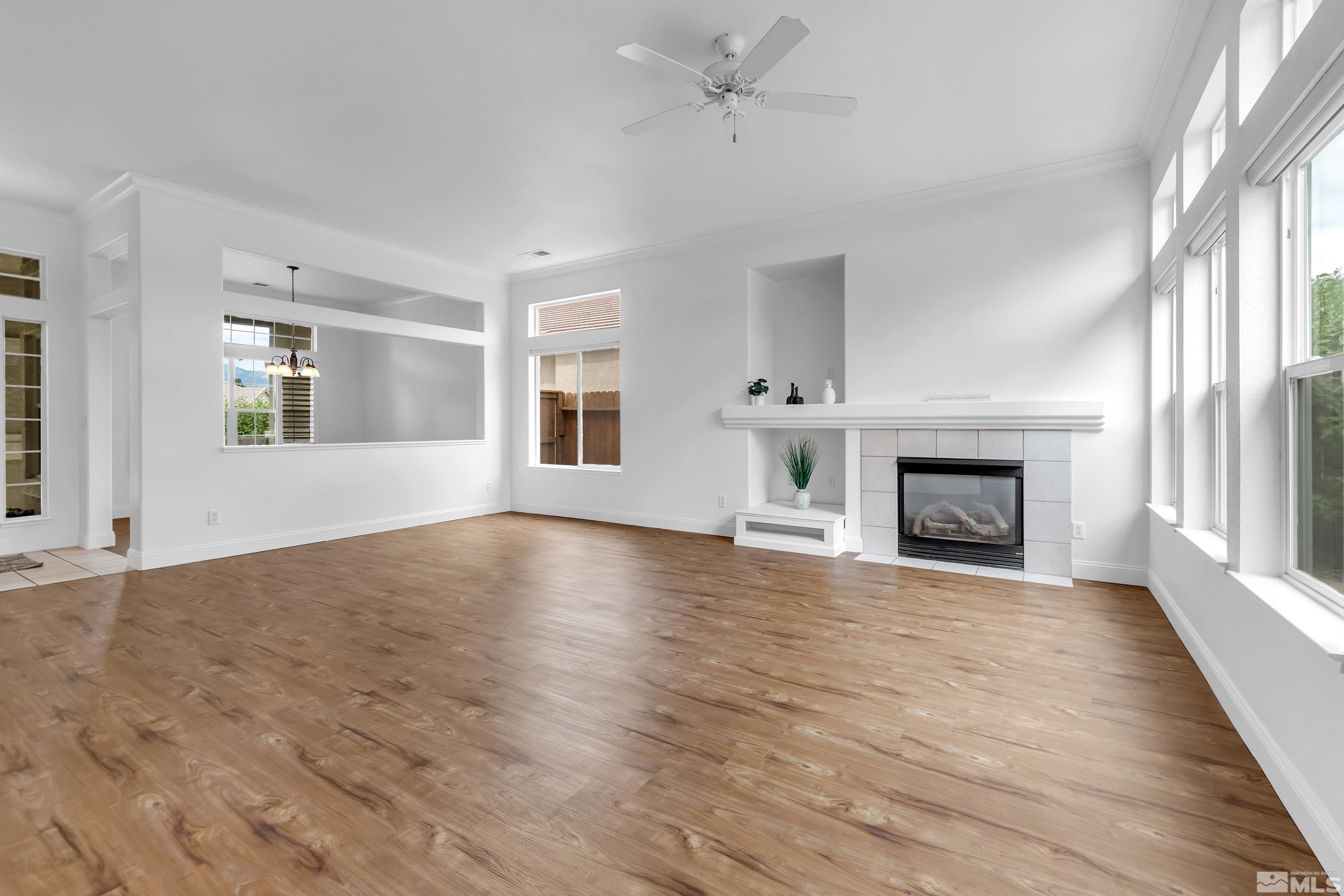 10445 Arbor Way Reno, NV 89521 - Photo 10 of 39 an empty room with wooden floor fireplace and windows