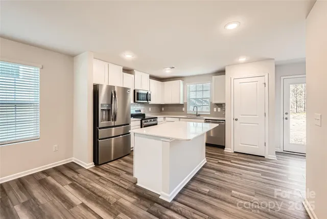 a kitchen with a refrigerator a sink and dishwasher with wooden floor