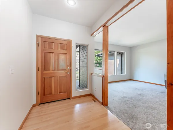 a view of an empty room with a window and kitchen view