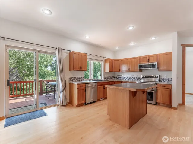 a large kitchen with stainless steel appliances kitchen island granite countertop a refrigerator and a stove top oven