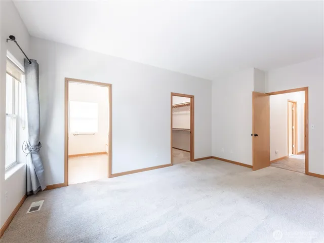 a spacious bathroom with a granite countertop double vanity sink a mirror and a toilet