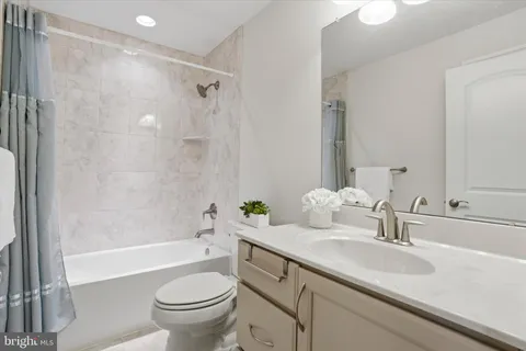 a bathroom with a granite countertop sink a toilet and a bathtub