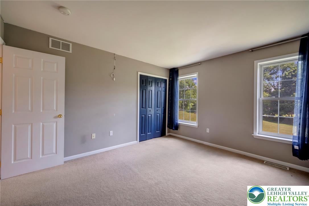 204 Bushkill Ridge Road Wind Gap, PA 18091 - Photo 32 of 48 Two bright windows illuminate this spacious room with plush carpet flooring, offering serene outdoor views.