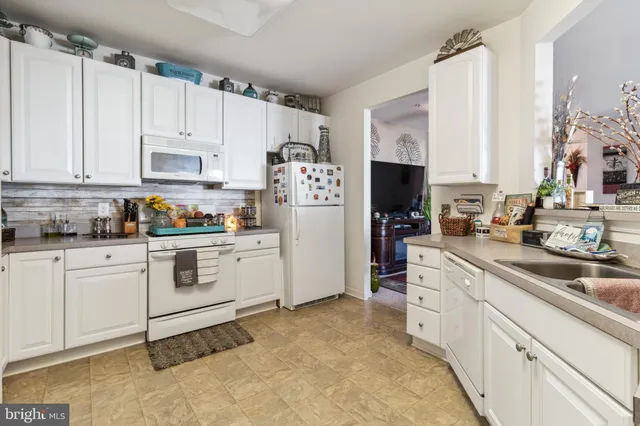 a kitchen with granite countertop white cabinets and white appliances