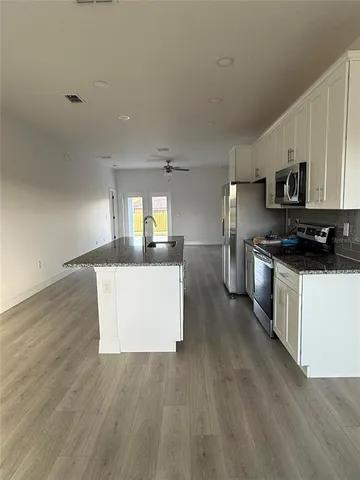 a kitchen with stainless steel appliances a refrigerator a stove a sink and white cabinets