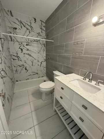 a bathroom with a granite countertop toilet a sink and mirror