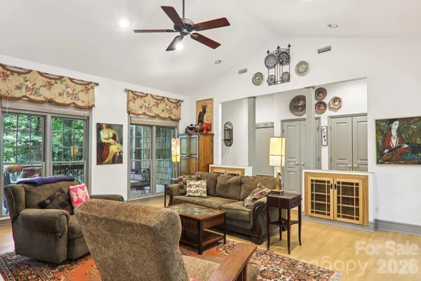 a living room with furniture kitchen view and large windows