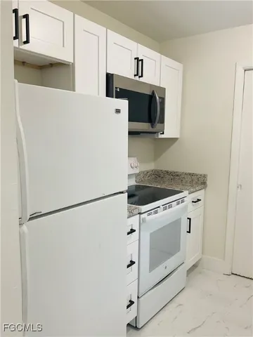 a kitchen with white cabinets and white appliances
