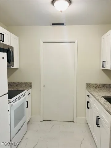 a kitchen with granite countertop white cabinets and sink