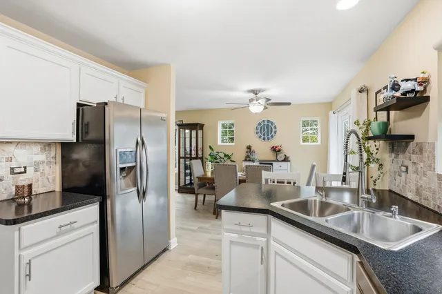 a kitchen with stainless steel appliances granite countertop a sink a refrigerator and white cabinets