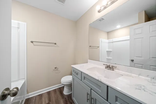 a bathroom with a granite countertop sink a toilet and a mirror