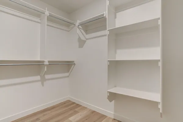 an empty room with a chandelier fan and wooden floor