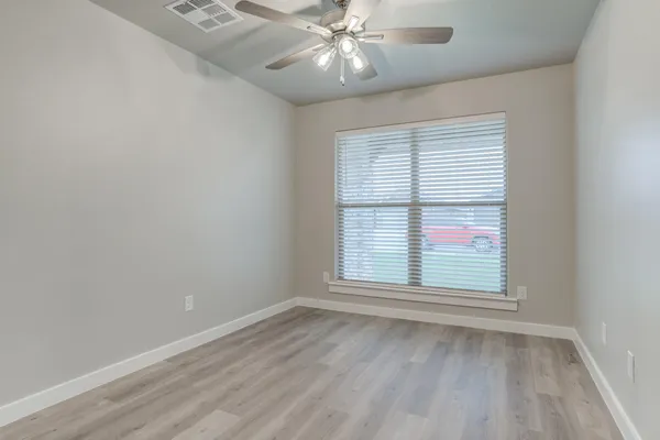 an empty room with a window and ceiling fan