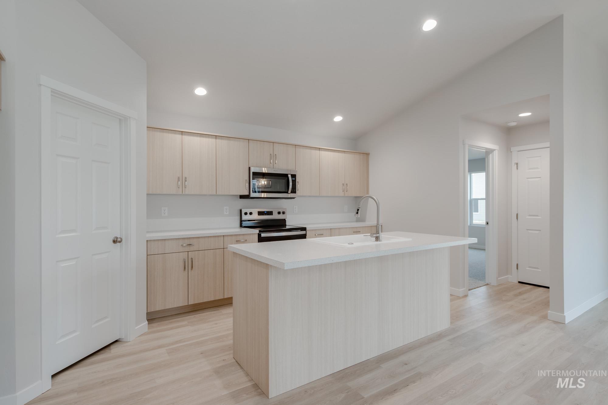 3090 South Maple Rnch Way Nampa, ID 83686 - Photo 4 of 22 Kitchen with light countertops, a center island with sink, light brown cabinetry, appliances with stainless steel finishes, and light wood finished floors