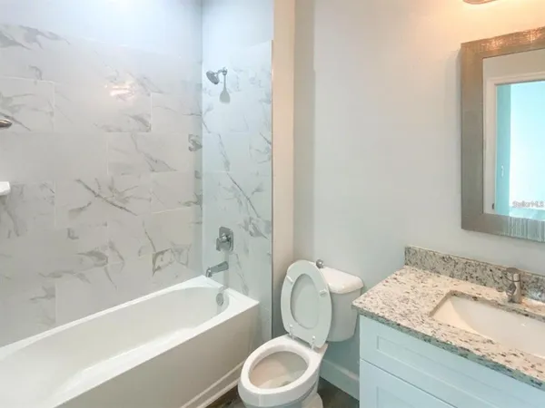 a bathroom with a granite countertop sink toilet a mirror and bathtub