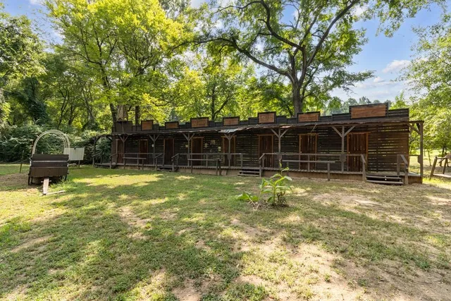 a view of a house with a backyard and a large tree
