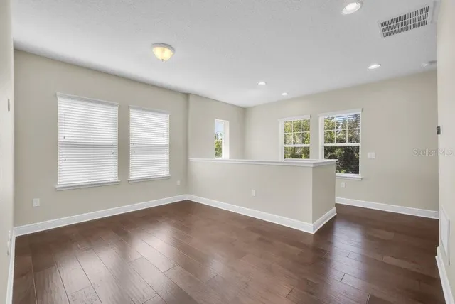 an empty room with wooden floor and windows