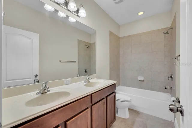 a bathroom with a double vanity sink a toilet and shower