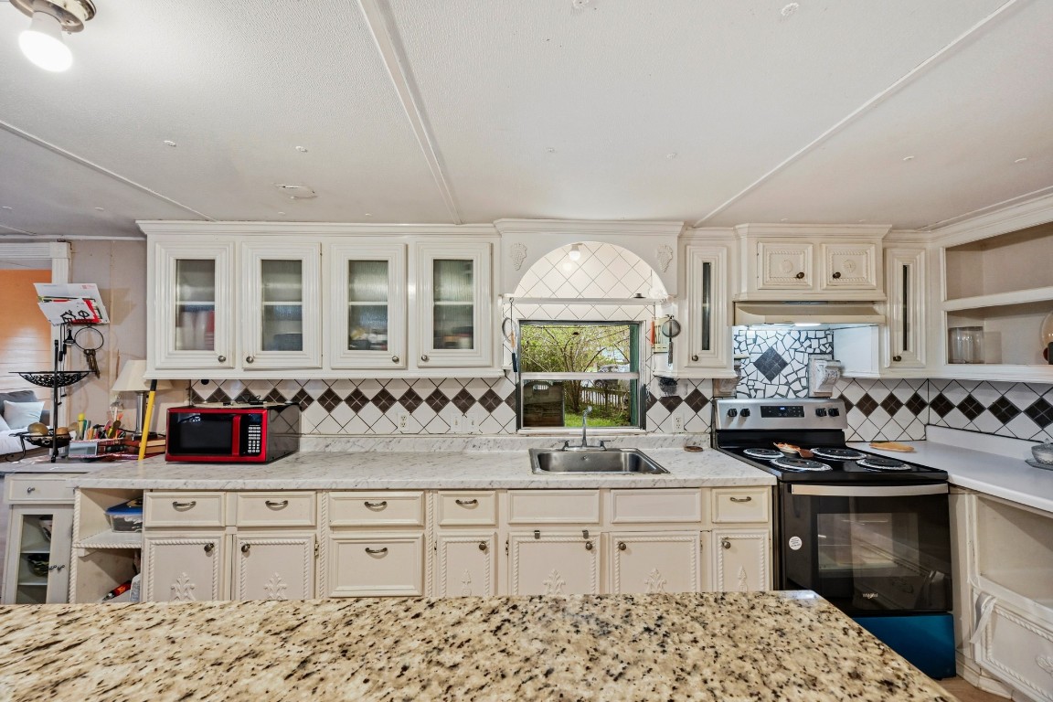 2137 Honey Tree Street Conroe, TX 77385 - Photo 4 of 13 a kitchen with granite countertop a sink stove and cabinets