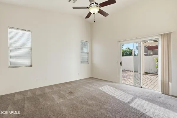 a view of an empty room with wooden floor and a ceiling fan
